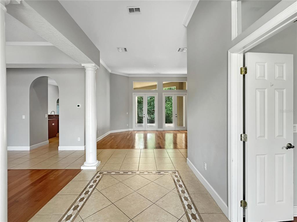 An entryway with tiled floors leads to a living area with hardwood floors and doors — 2770 REGAL PINE TRAIL, OVIEDO, FL