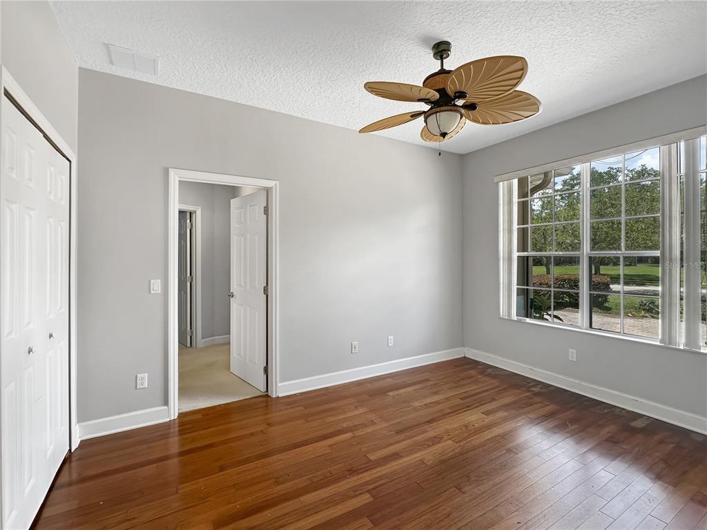 An empty bedroom features light gray walls, dark wood flooring, and a tropical-style ceiling fan — 2770 REGAL PINE TRAIL, OVIEDO, FL