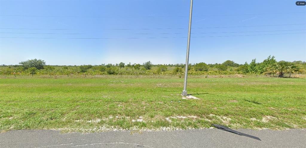 A grassy, undeveloped lot features a utility pole and a wire fence under a clear sky — HESPERIDES ROAD, LAKE WALES, FL