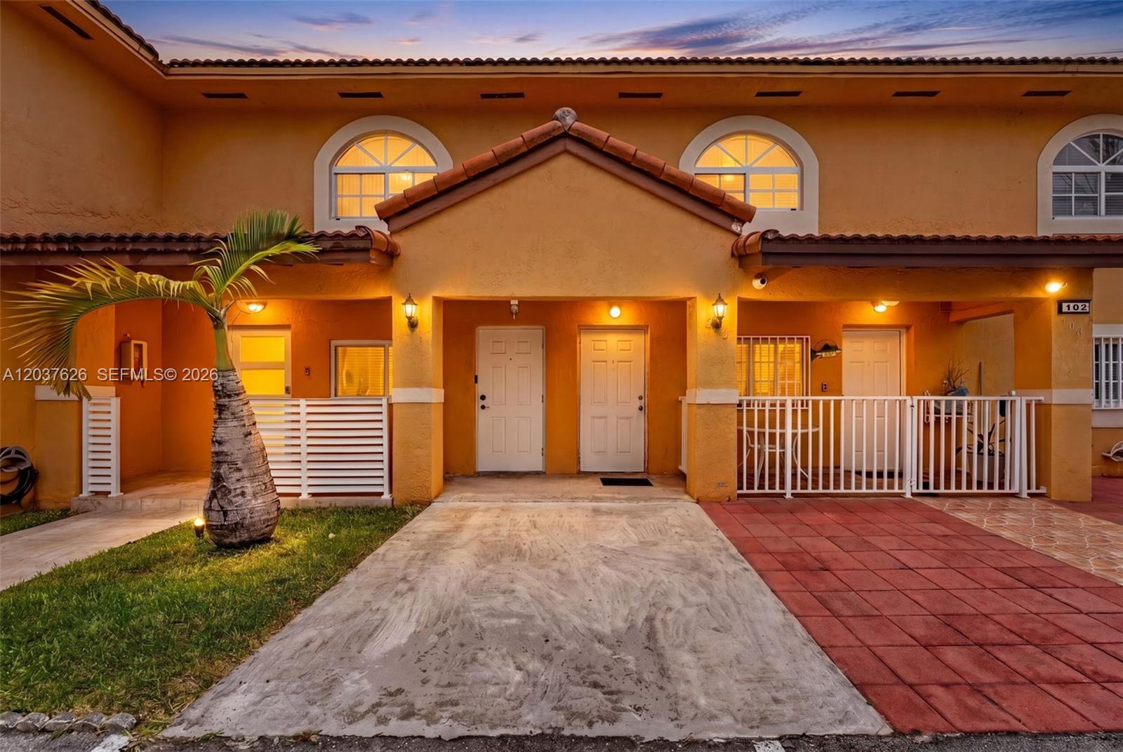 The exterior of a two-story stucco townhouse features a concrete driveway and a palm tree — 3574 W 80th St # 201, Hialeah FL 33018, HIALEAH, FL