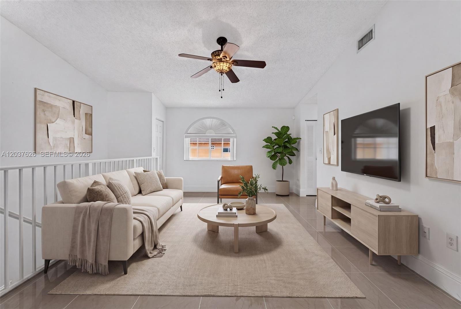 A living room features a beige sofa, a round wooden coffee table, and a wall-mounted television — 3574 W 80th St # 201, Hialeah FL 33018, HIALEAH, FL