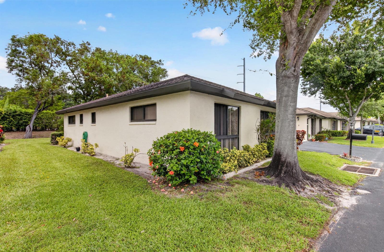 A single-story beige house with a flat roof, landscaping, and a large tree in front — 4944 Equestrian Circle # A, Boynton Beach FL 33436, BOYNTON BEACH, FL