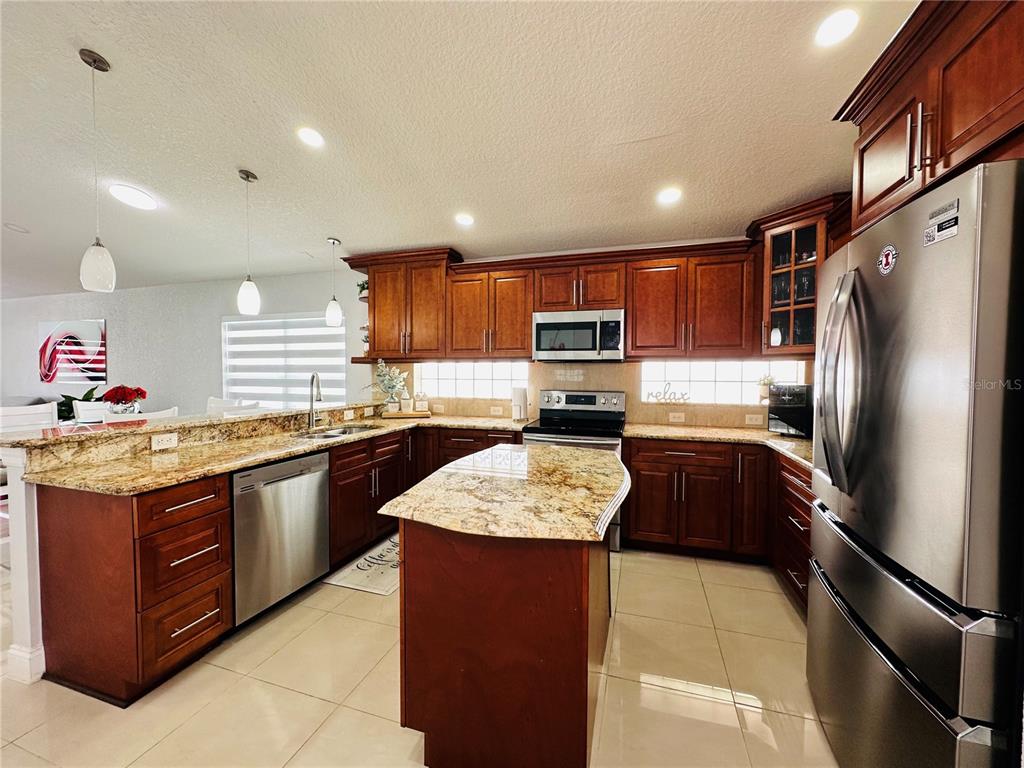 A kitchen features dark wood cabinets, granite countertops, stainless steel appliances, and a central island — 8885 PALISADES BEACH AVENUE, ORLANDO, FL