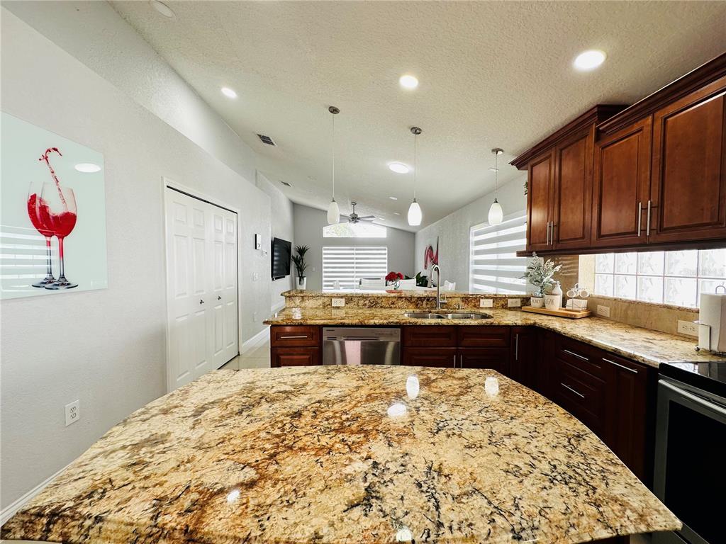 A kitchen features dark wood cabinets, granite countertops, a central island, and recessed lighting — 8885 PALISADES BEACH AVENUE, ORLANDO, FL