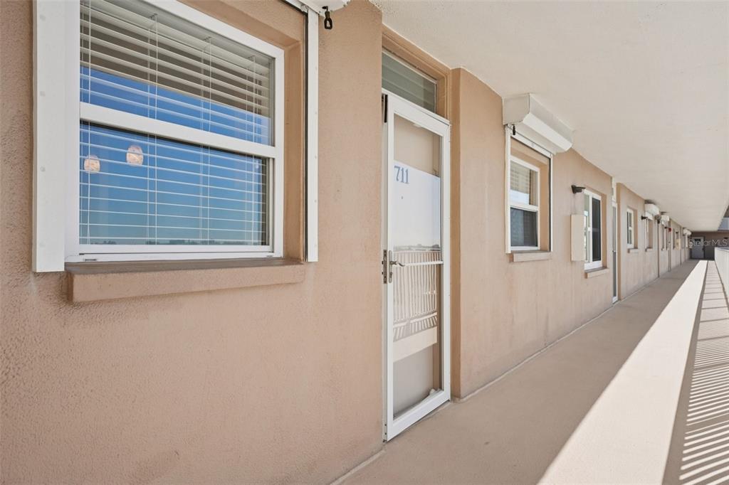 An exterior view of a building walkway featuring a door labeled 711 and windows — 1847 SHORE DRIVE S UNIT 711, SOUTH PASADENA, FL