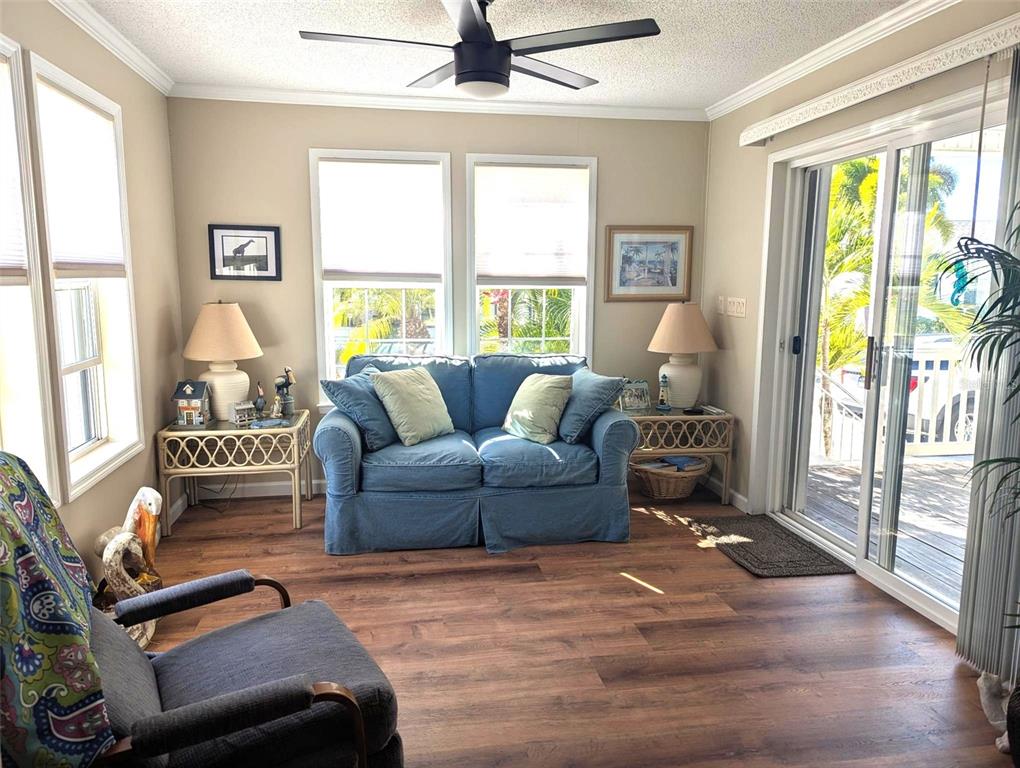 A sunroom features a blue sofa, two side tables with lamps, and wood-look flooring — 2100 KINGS HWY UNIT 1094, PORT CHARLOTTE, FL