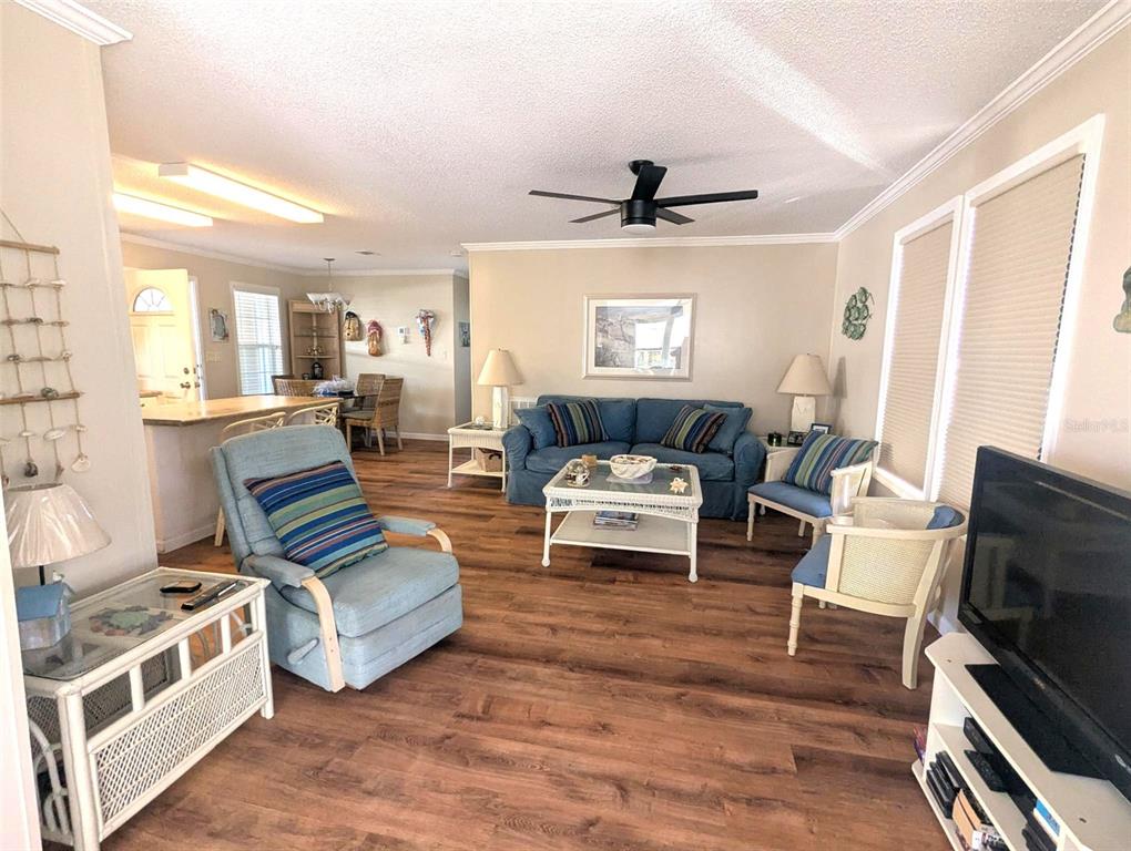 A living room with wood-look flooring, a blue sofa, and a matching armchair — 2100 KINGS HWY UNIT 1094, PORT CHARLOTTE, FL