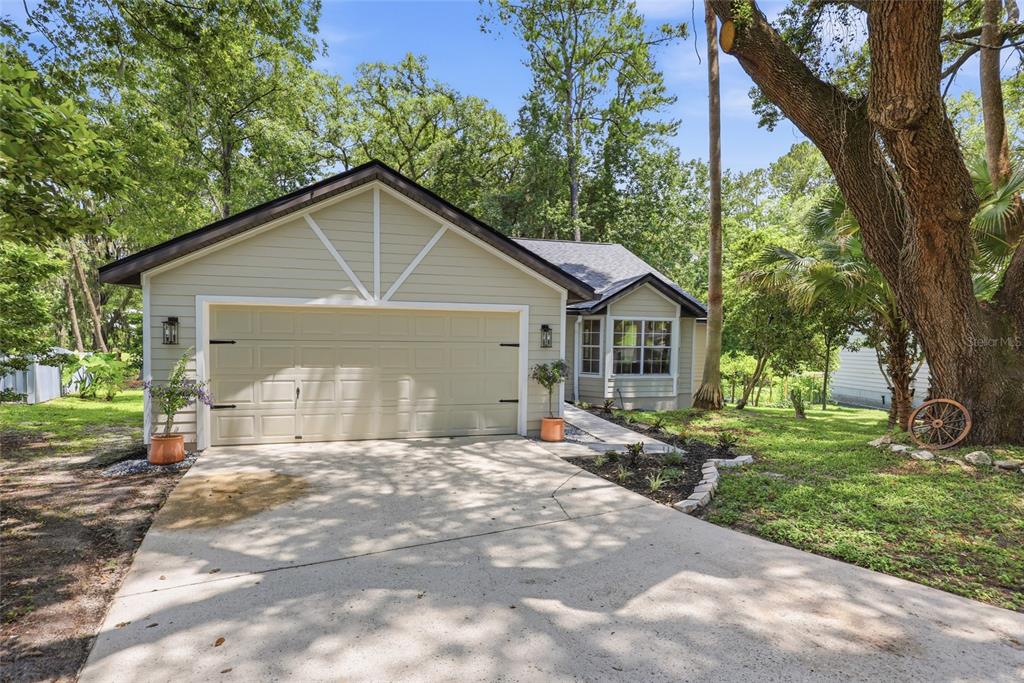 A single-story house with light siding, a two-car garage, and a large tree in front — 3543 NW 84TH WAY, GAINESVILLE, FL