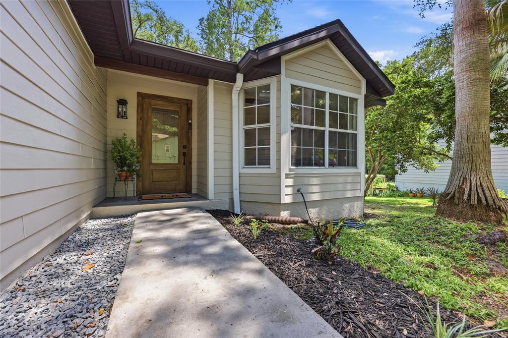 A concrete walkway leads to the front entrance of a house with beige siding — 3543 NW 84TH WAY, GAINESVILLE, FL