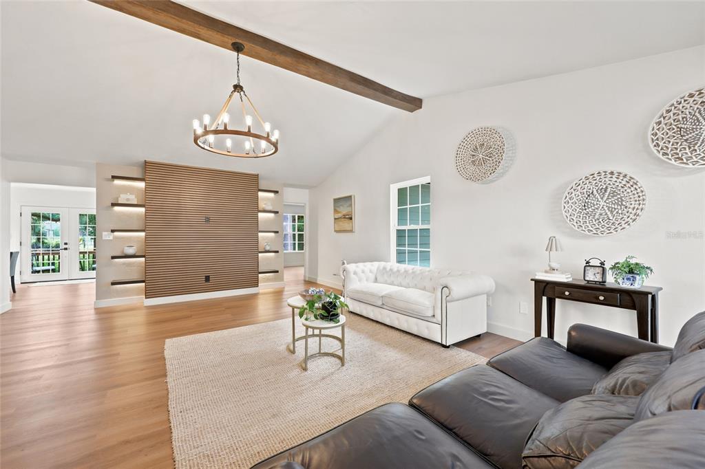 A living room features a wood-slat accent wall, a vaulted ceiling with a beam, and furniture — 3543 NW 84TH WAY, GAINESVILLE, FL
