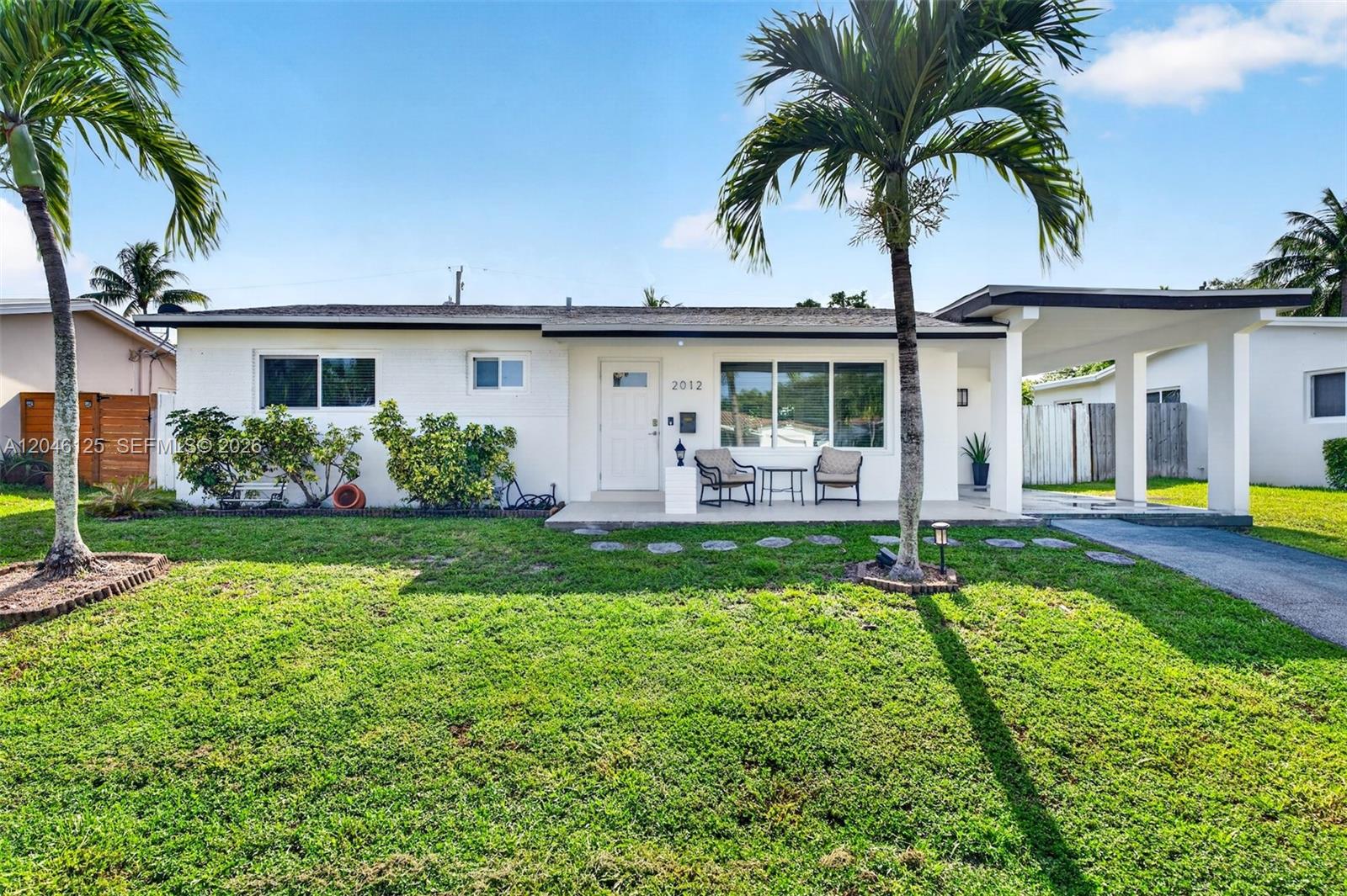 A white single-story house features a front porch, a carport, and two palm trees — 2012 N 31st Rd, Hollywood FL 33021, HOLLYWOOD, FL