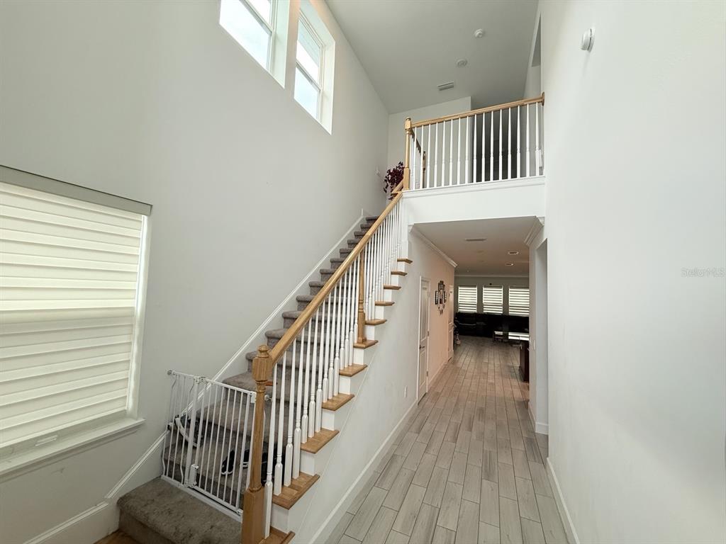 An entryway features a staircase with a white railing and light-colored tile flooring — 16318 HONEY HARVEST STREET, WINTER GARDEN, FL