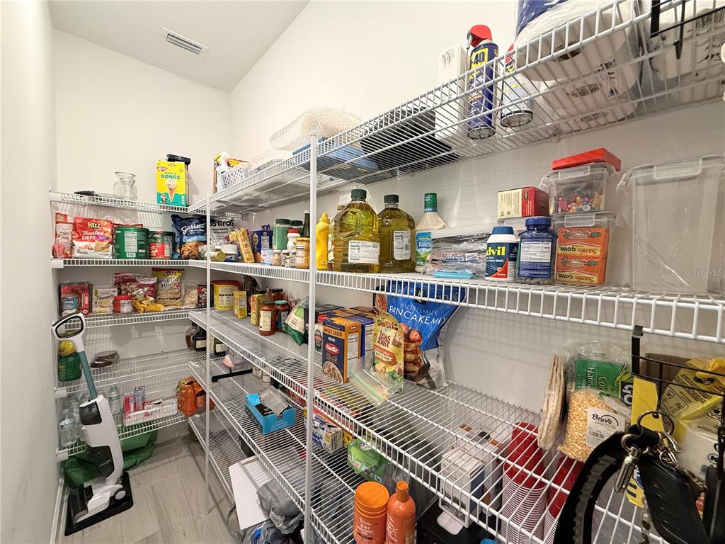 A walk-in pantry features white wire shelving units filled with various food items and supplies — 16318 HONEY HARVEST STREET, WINTER GARDEN, FL