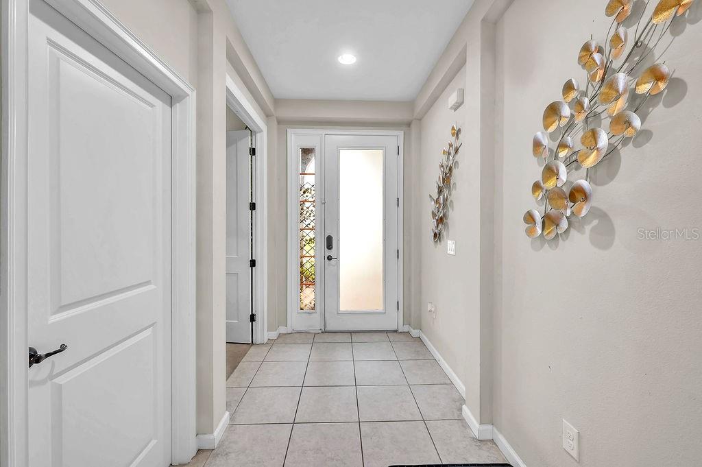 A tiled entryway features a white front door with sidelights and decorative wall art — 189 TRINITY RIDGE CIRCLE, DAVENPORT, FL