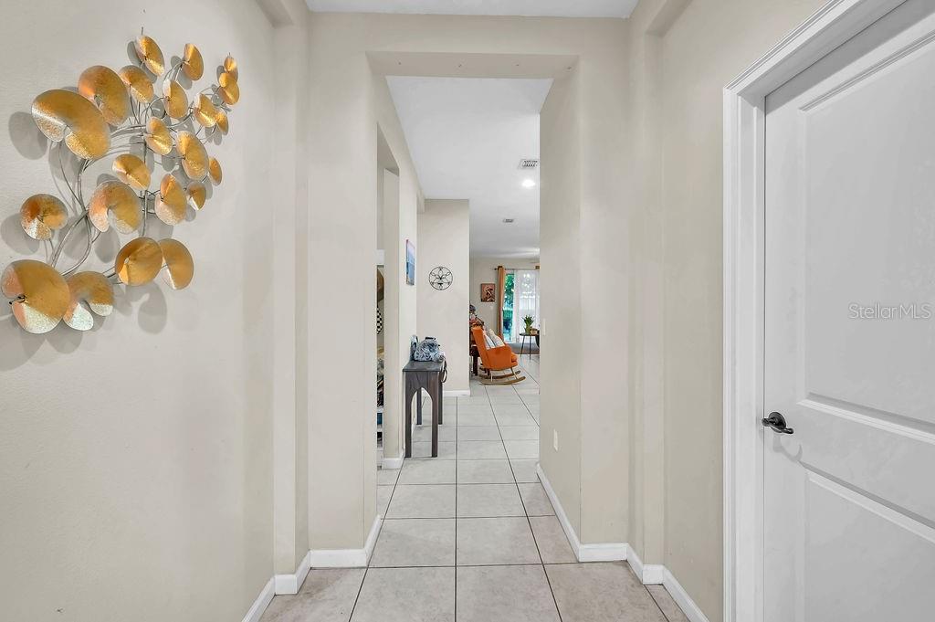A tiled entryway leads into a living area with a gold wall sculpture and furniture — 189 TRINITY RIDGE CIRCLE, DAVENPORT, FL