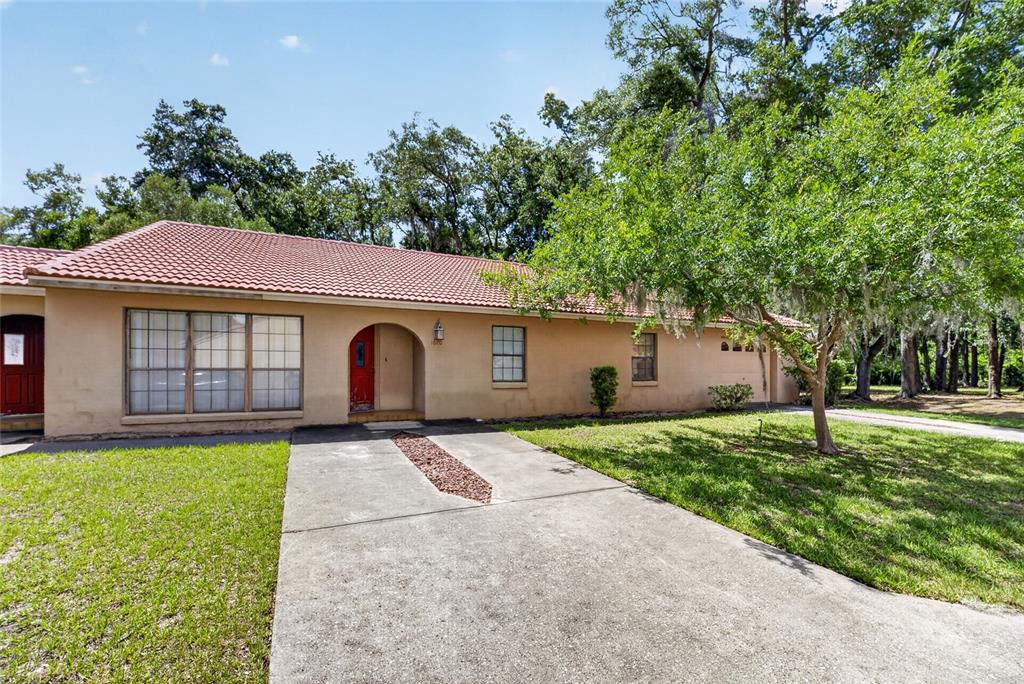 A single-story house with a red tile roof, tan stucco exterior, and a concrete driveway — 1826 SW 35TH AVENUE, OCALA, FL