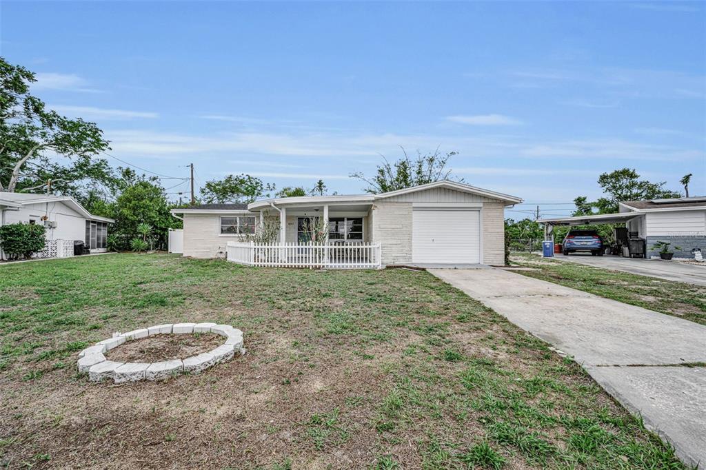 A single-story house with a white brick exterior, a garage, and a fenced front porch — 4843 CALAIS DRIVE, HOLIDAY, FL
