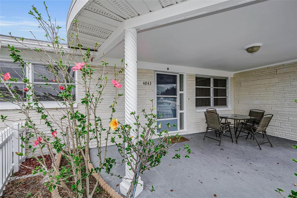 A covered patio features a white spiral column, brick-textured walls, and a small dining set — 4843 CALAIS DRIVE, HOLIDAY, FL