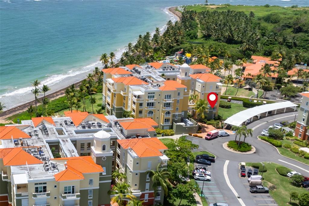 An aerial view shows multi-story apartment buildings with orange roofs near a sandy beach — 200 OCEAN DRIVE UNIT 245, HUMACAO, PR
