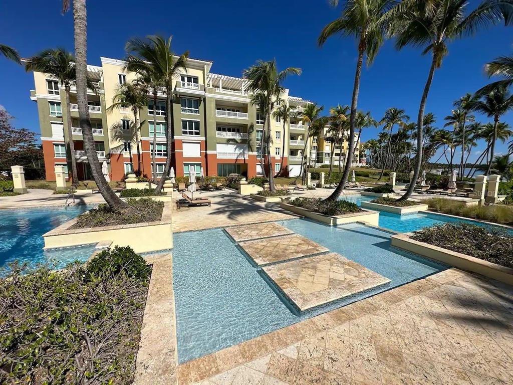 A multi-story apartment building overlooks a swimming pool with stone walkways and palm trees — 200 OCEAN DRIVE UNIT 245, HUMACAO, PR