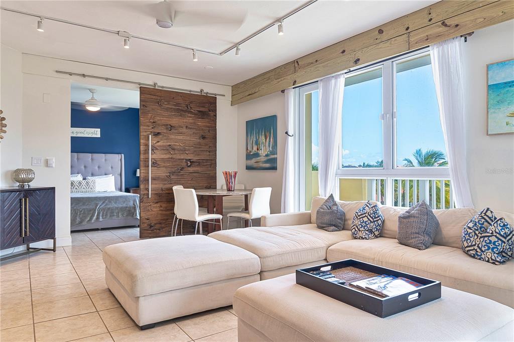 A living room with a sectional sofa, dining area, and sliding barn door to a bedroom — 200 OCEAN DRIVE UNIT 245, HUMACAO, PR