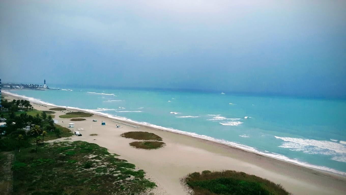 An elevated view of a sandy beach with turquoise water and a distant lighthouse — 1012 N Ocean Boulevard # 602, Pompano Beach FL 33062, POMPANO BEACH, FL