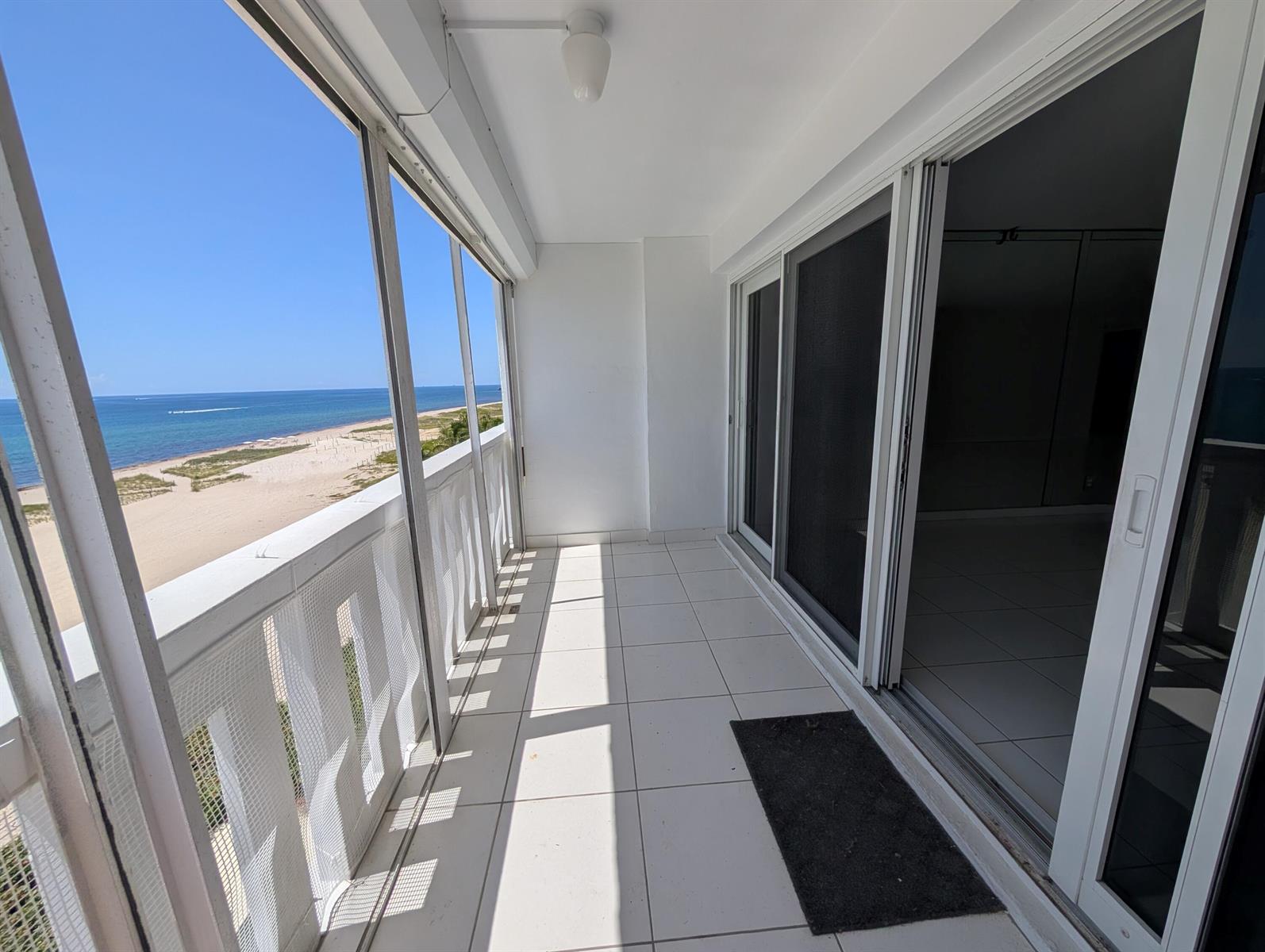 A white-tiled balcony with a screen enclosure overlooks a sandy beach and the ocean — 1012 N Ocean Boulevard # 602, Pompano Beach FL 33062, POMPANO BEACH, FL