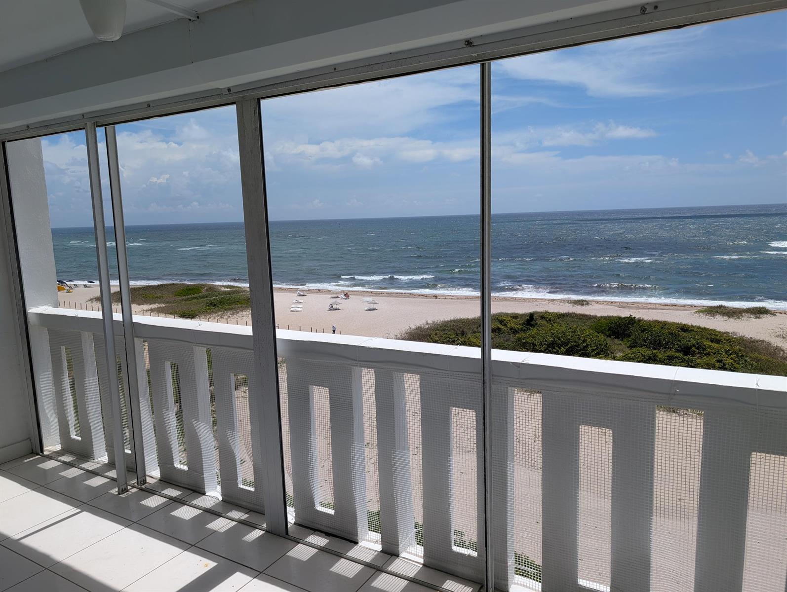 A screened balcony with white railings overlooks a sandy beach and the ocean — 1012 N Ocean Boulevard # 602, Pompano Beach FL 33062, POMPANO BEACH, FL