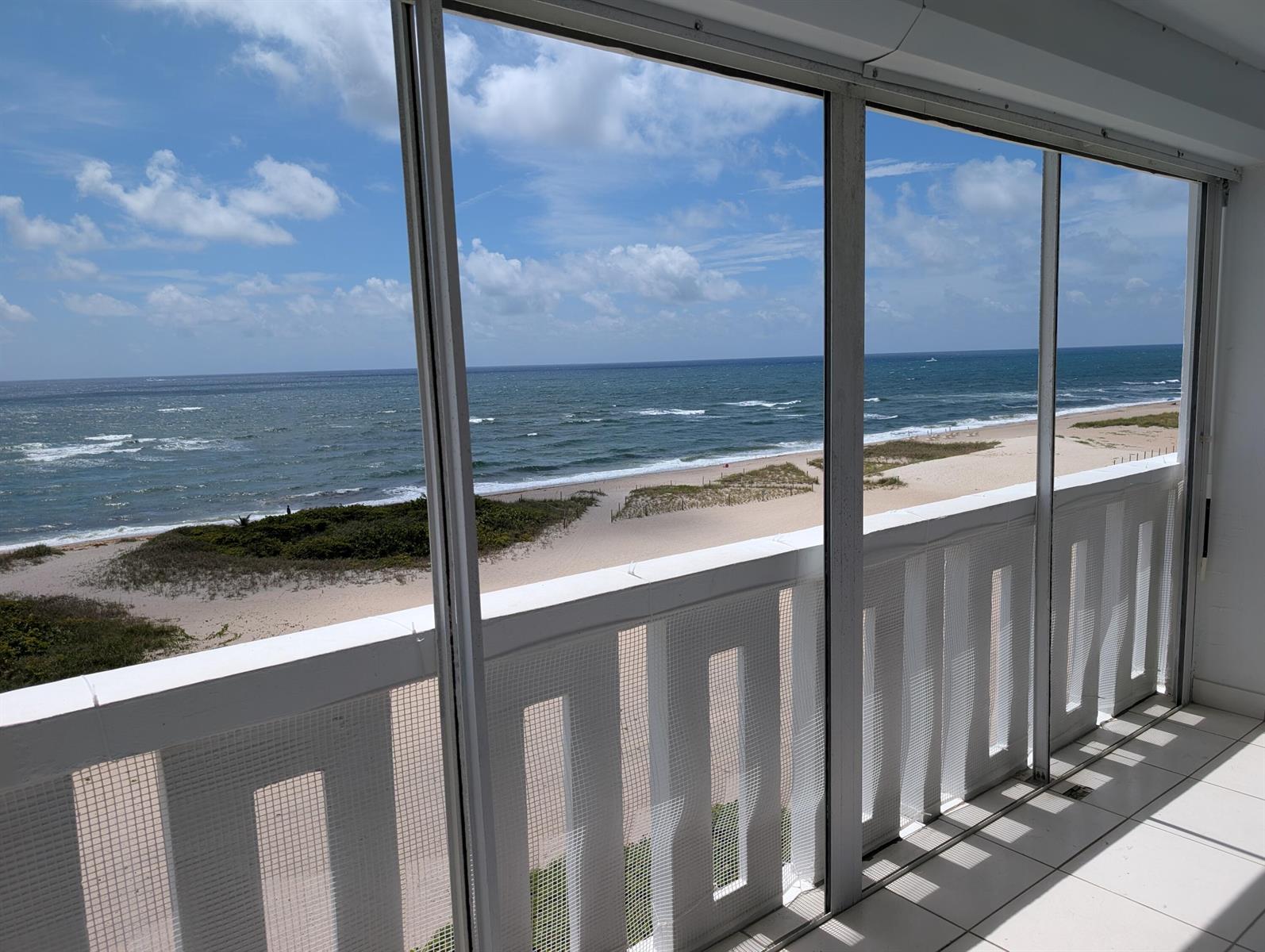 A screened-in balcony with white railings overlooks a sandy beach and the ocean — 1012 N Ocean Boulevard # 602, Pompano Beach FL 33062, POMPANO BEACH, FL