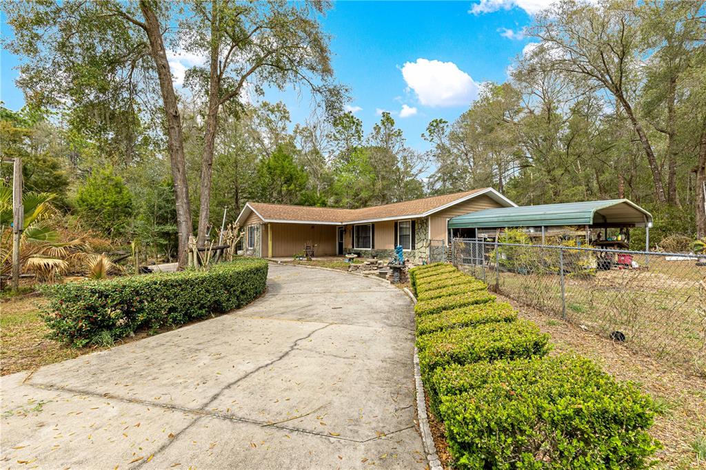 A single-story house with a concrete driveway, a carport, and manicured hedges in the yard — 4551 SW 129TH COURT, OCALA, FL