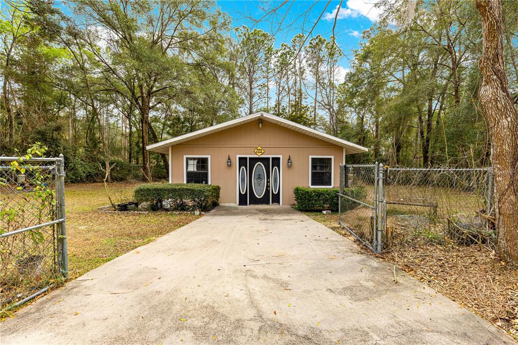 A tan, single-story detached building with a concrete driveway and a fenced yard — 4551 SW 129TH COURT, OCALA, FL