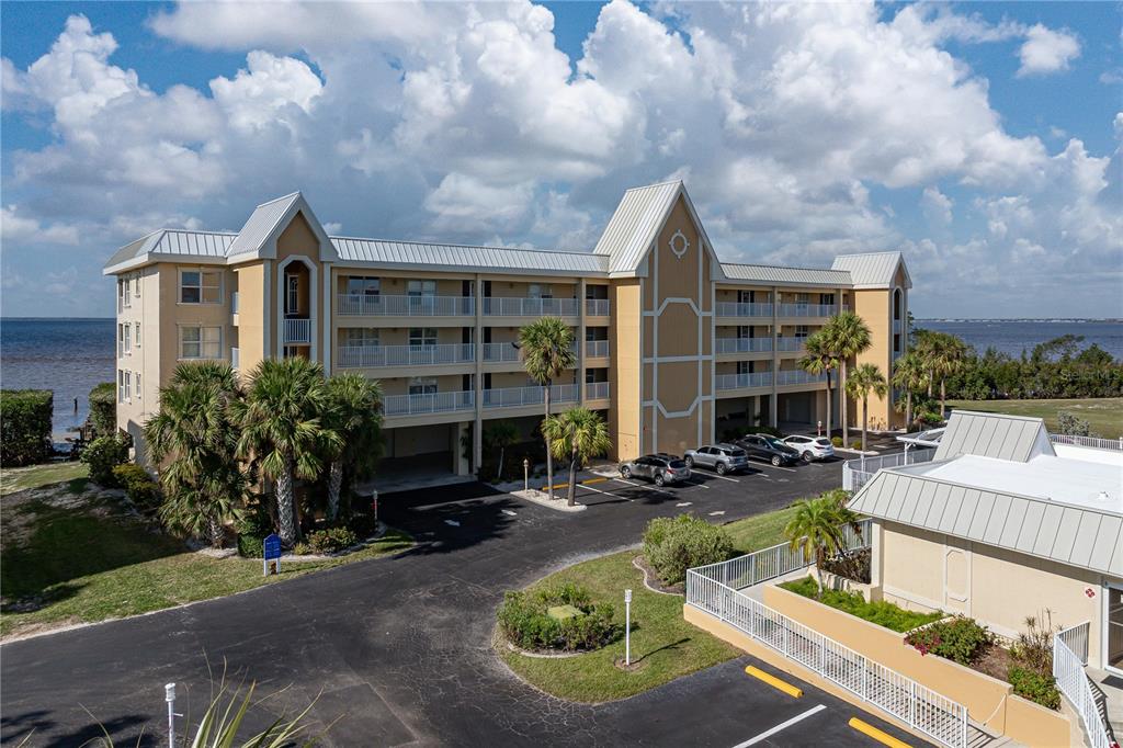 An exterior view of a multi-story apartment building with balconies and a parking lot — 101 N MARION COURT UNIT 221, PUNTA GORDA, FL