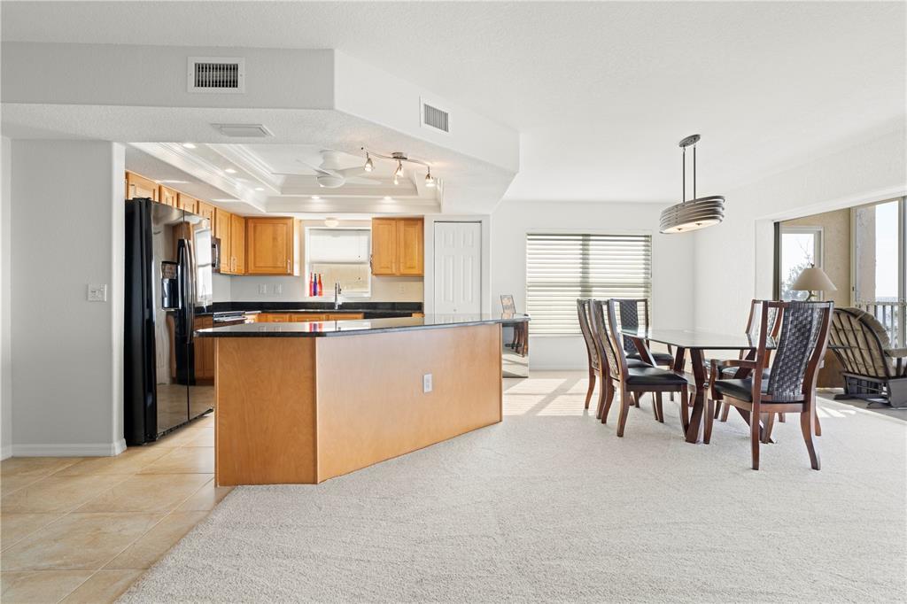 An open-concept kitchen with wood cabinets and a black island overlooks a dining area — 101 N MARION COURT UNIT 221, PUNTA GORDA, FL