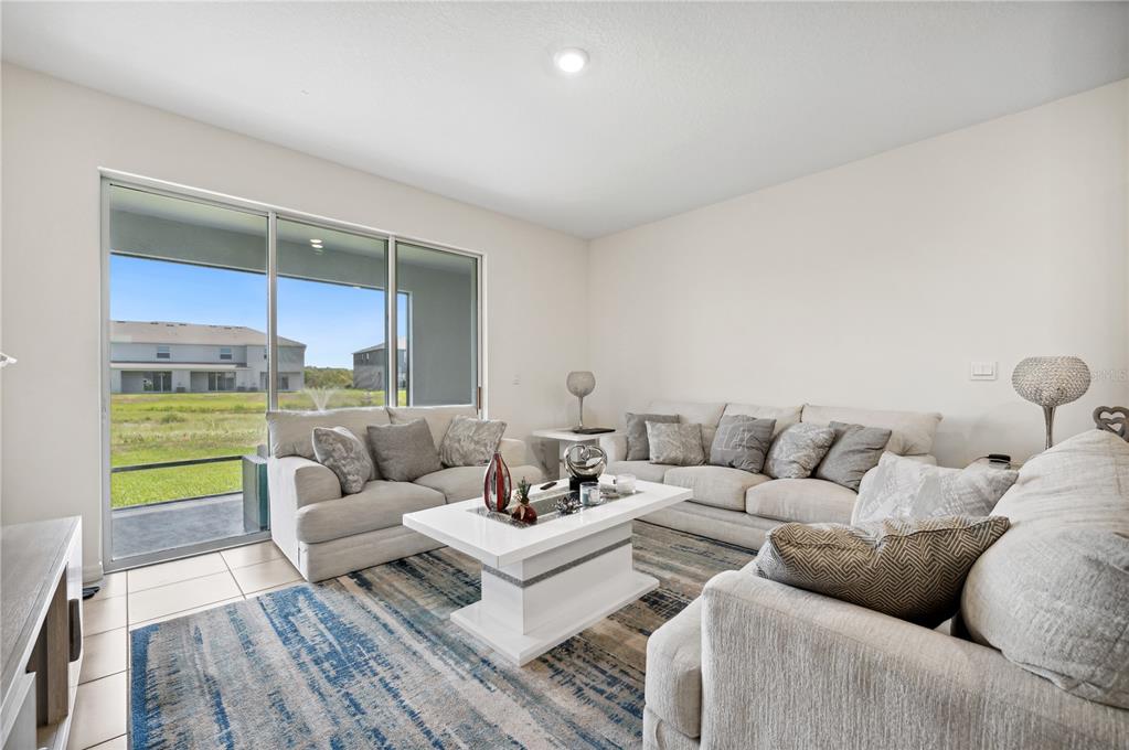 A living room features light-colored sofas, a white coffee table, and sliding glass doors — 8924 MILESTONE DRIVE, SARASOTA, FL