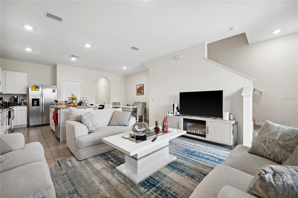 An open-concept living room features a white sofa, a coffee table, and a television console — 8924 MILESTONE DRIVE, SARASOTA, FL