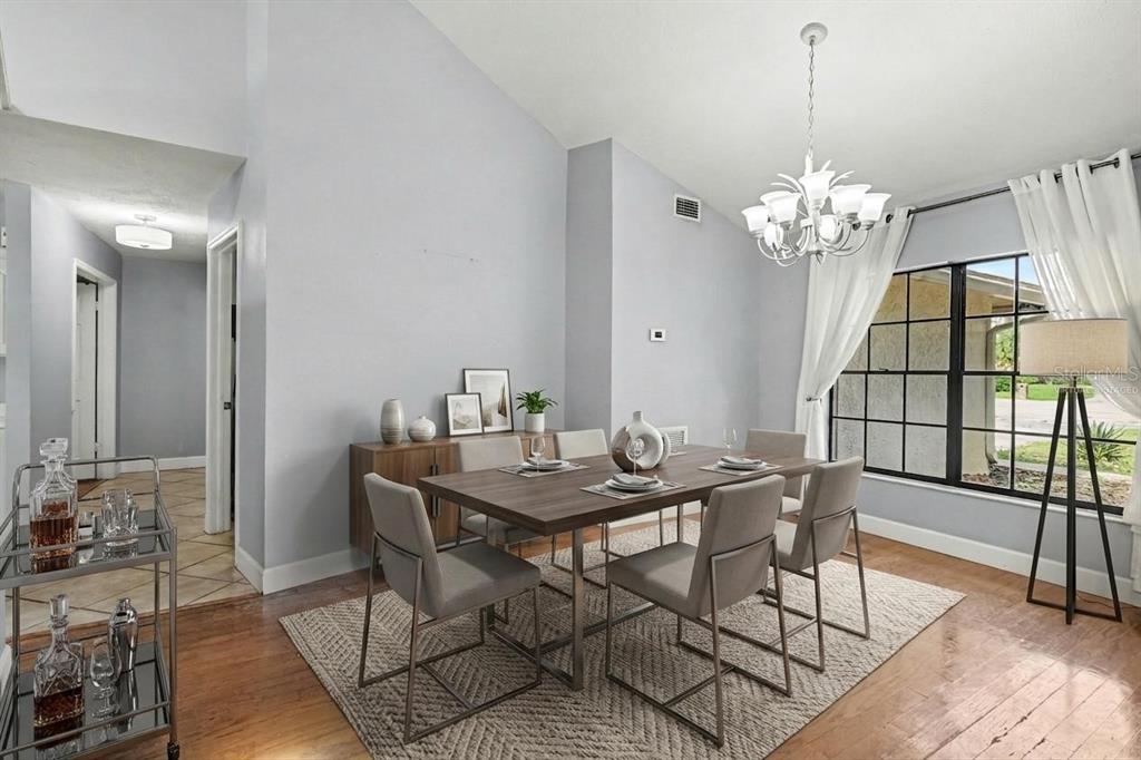 A dining room features a wooden table, six chairs, and a chandelier under vaulted ceilings — 4504 DEER PARK PLACE, BRANDON, FL
