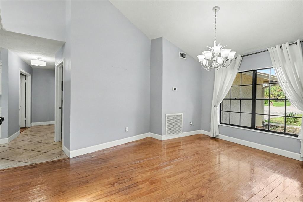 A dining room features a wooden table, six chairs, a chandelier, and a large window — 4504 DEER PARK PLACE, BRANDON, FL