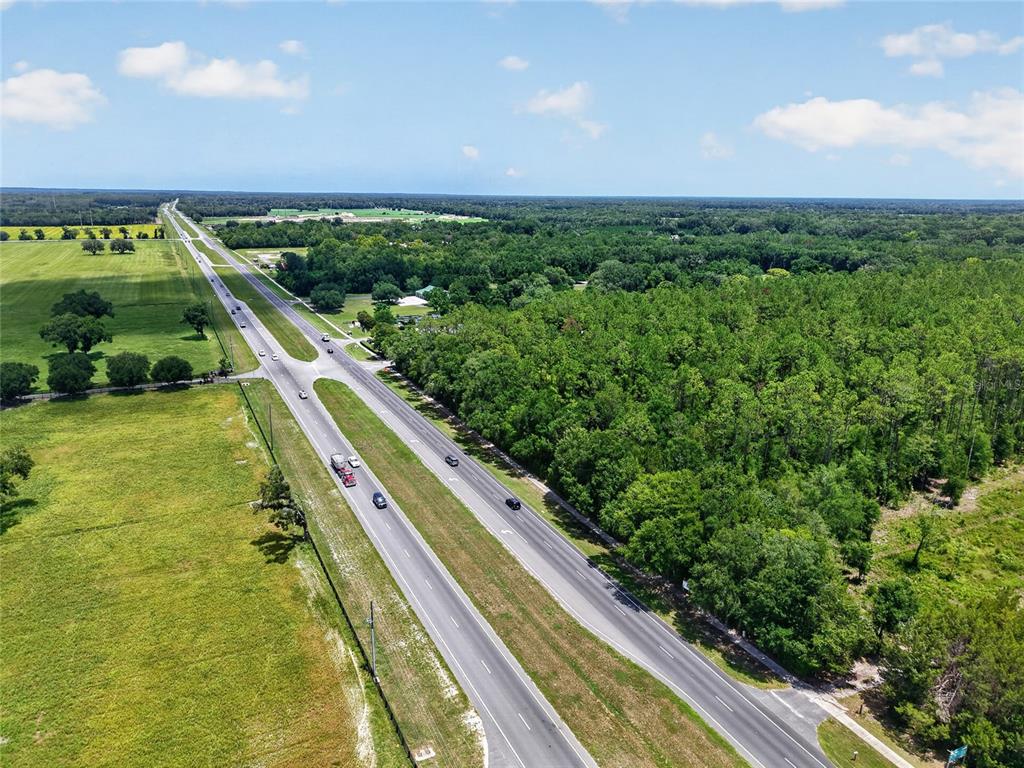 An aerial view shows a divided highway running between a grassy field and dense woods — 000 W NEWBERRY ROAD, NEWBERRY, FL