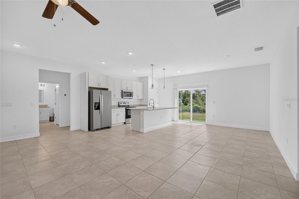 An open-concept kitchen with white cabinets, stainless steel appliances, and tile flooring — 15475 SW 23RD AVENUE ROAD, OCALA, FL