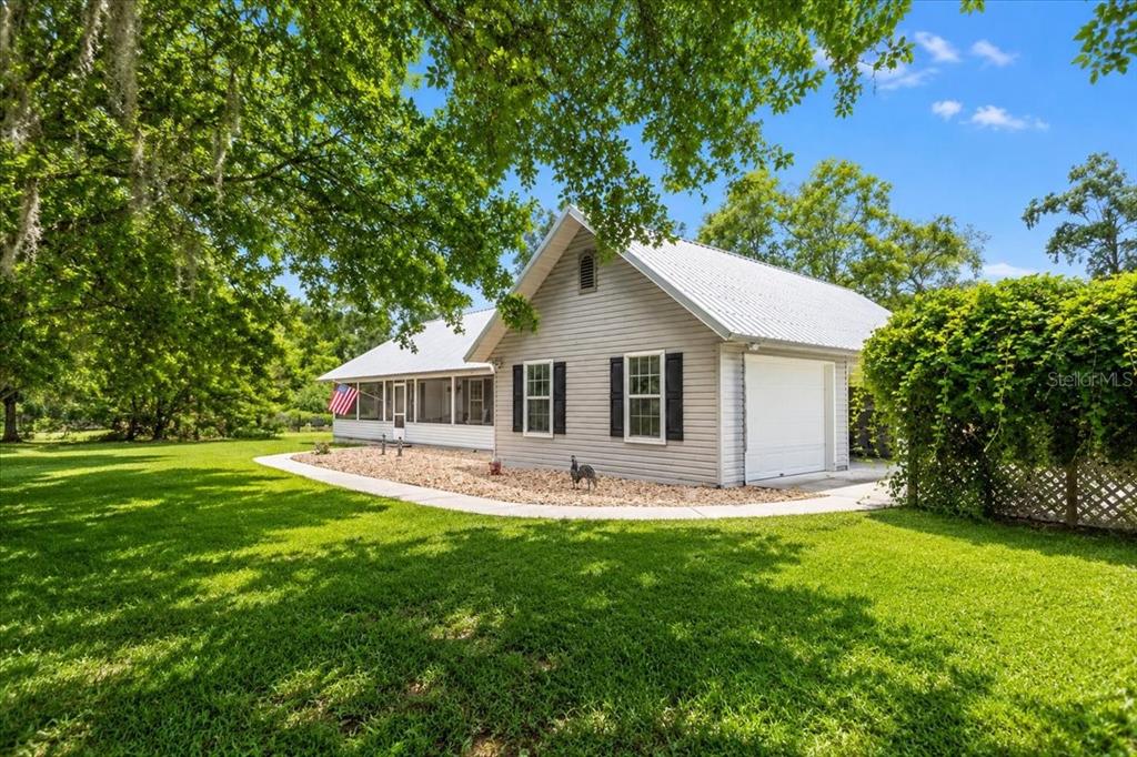 A light gray house with a metal roof, attached garage, and a screened-in porch — 25419 NW 105TH PLACE, HIGH SPRINGS, FL