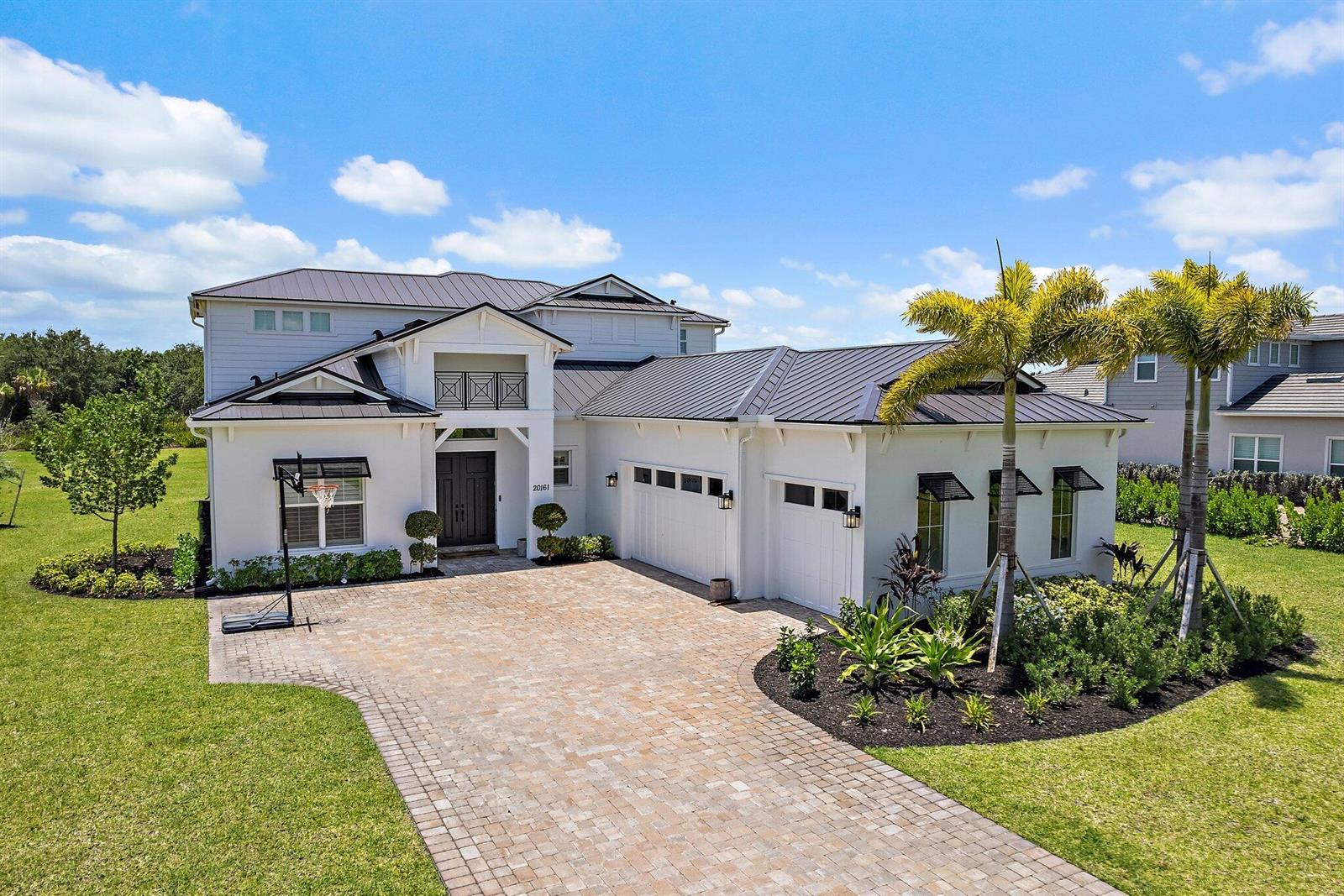 A two-story white house with a metal roof and a paved driveway — 20161 SE Bridgewater Drive, Jupiter FL 33458, JUPITER, FL