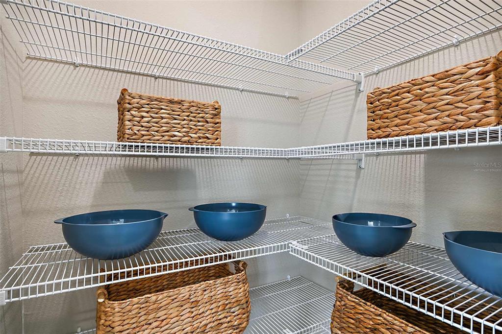 A walk-in pantry features white wire shelving, woven storage baskets, and blue mixing bowls — 5019 OAKS RIVER STREET, DAVENPORT, FL
