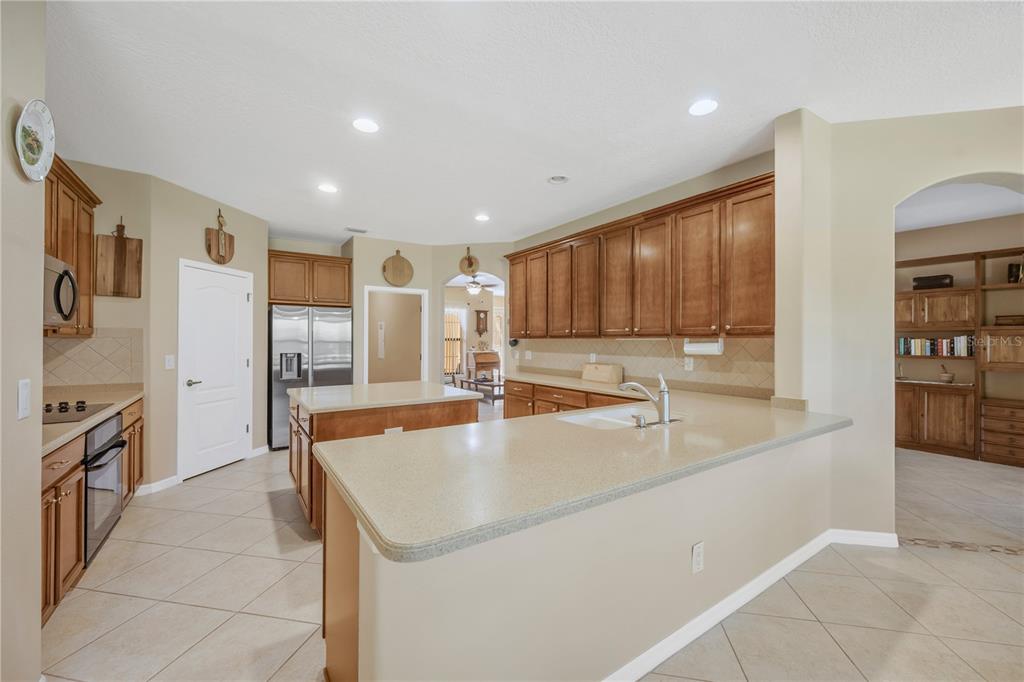 A kitchen features light-colored countertops, wood cabinetry, stainless steel appliances, and tile flooring — 9313 LISBON STREET, SEFFNER, FL