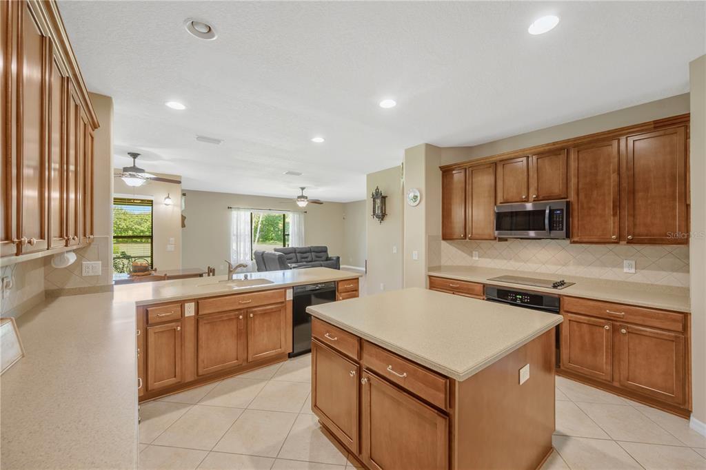 A kitchen features wood cabinets, a central island, beige countertops, and tile flooring — 9313 LISBON STREET, SEFFNER, FL