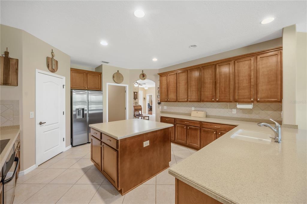 A kitchen with wood cabinets, stainless steel appliances, a center island, and tile flooring — 9313 LISBON STREET, SEFFNER, FL