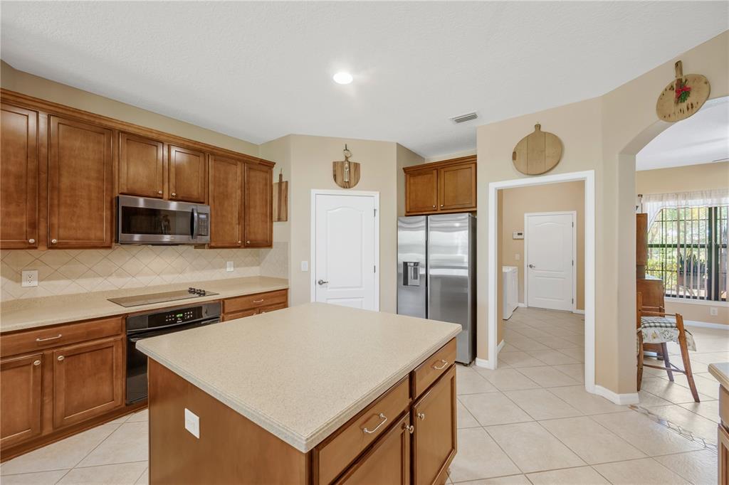 A kitchen features wood cabinets, stainless steel appliances, a center island, and beige countertops — 9313 LISBON STREET, SEFFNER, FL