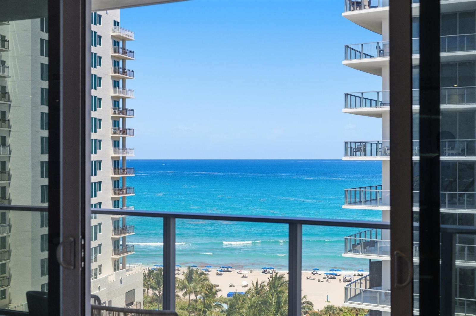 A view of the ocean and beach framed by two high-rise buildings from a balcony — 3100 N Ocean Drive # 1202, Singer Island FL 33404, SINGER ISLAND, FL