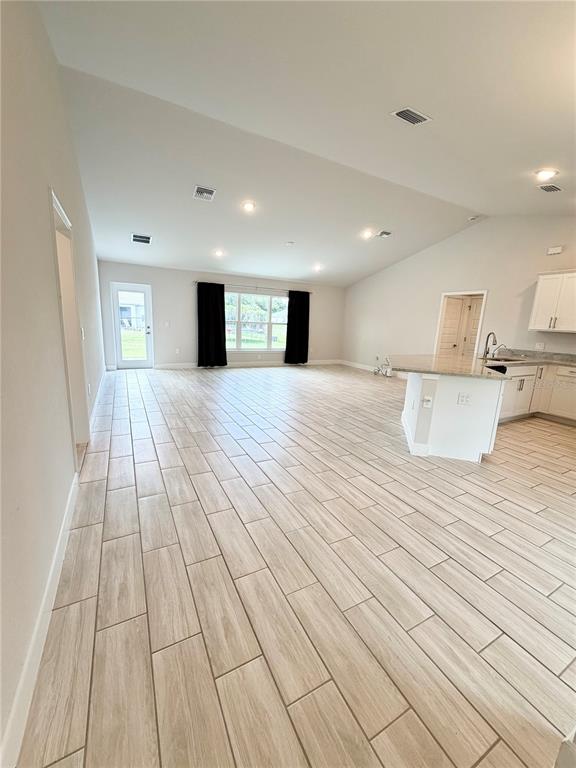 An open-concept living area features light wood-look tile flooring, recessed lighting, and a kitchen island — 4865 MANILA AVENUE, NORTH PORT, FL