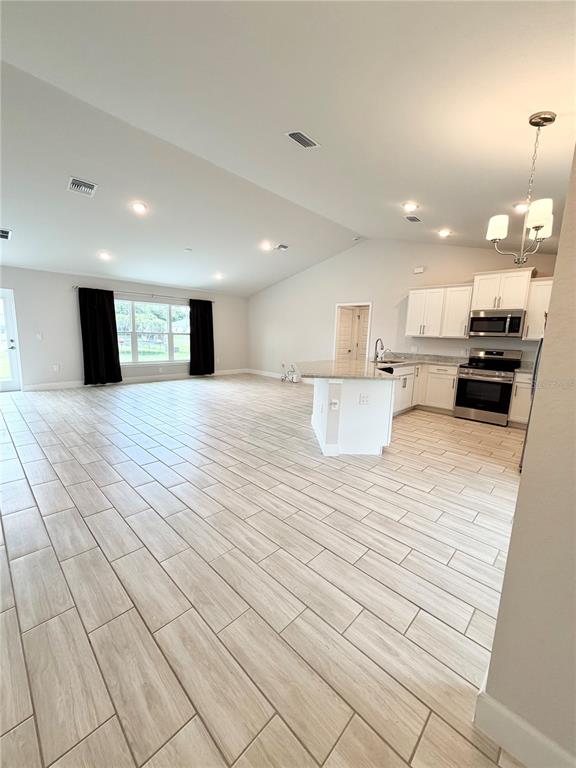 An open-concept kitchen and living area features white cabinetry, stainless steel appliances, and tile flooring — 4865 MANILA AVENUE, NORTH PORT, FL