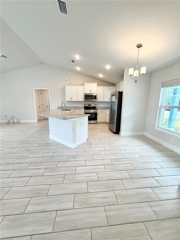 A kitchen with white cabinets, a granite island, and light wood-look tile flooring — 4865 MANILA AVENUE, NORTH PORT, FL